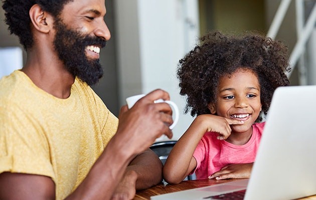 Daughter and father smiling in front of laptop.