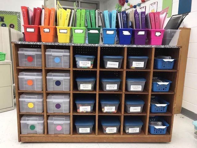Color-coded bookshelf with different colored binders and bins
