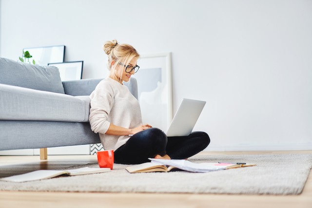 Woman sitting in front of her couch on laptop
