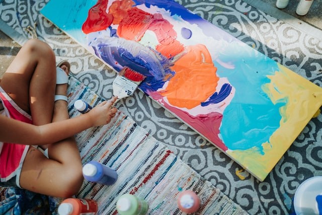 A child expressing themselves by painting on a canvas.