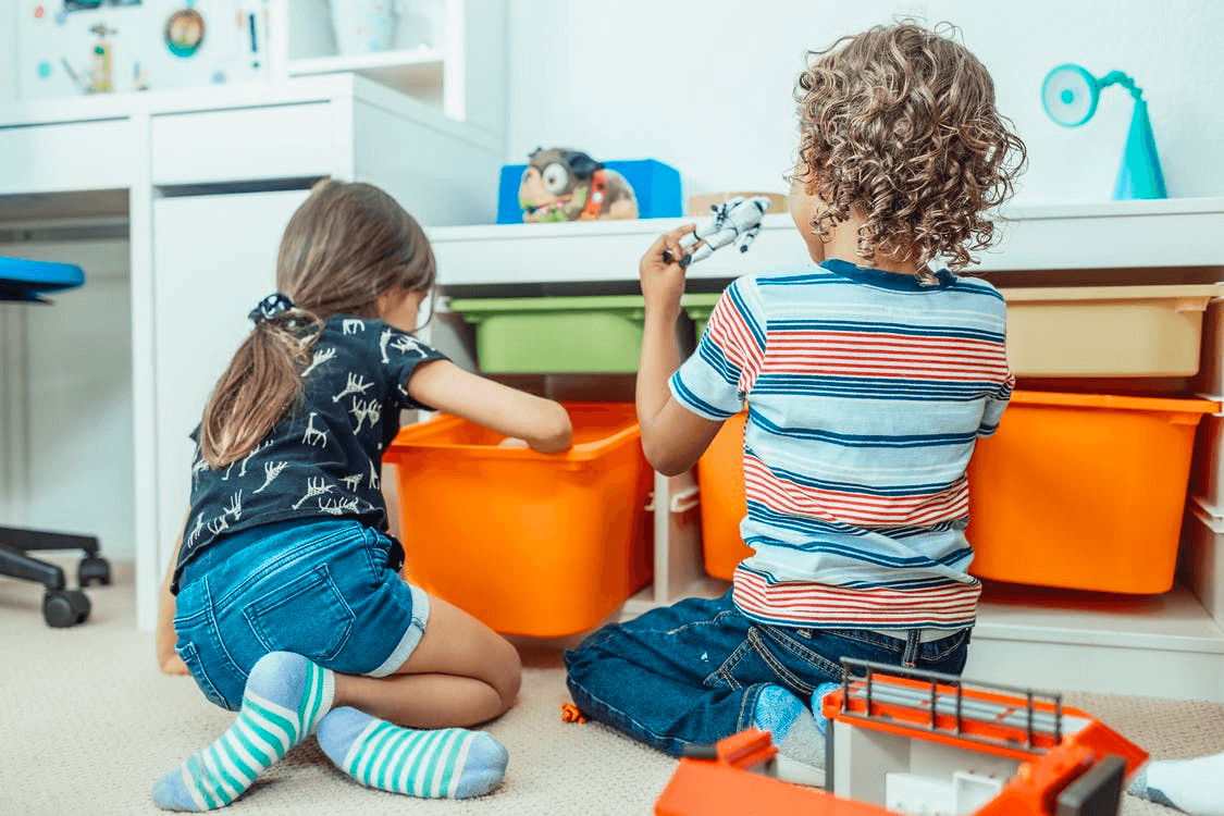 Two children rummage through toy bins during a playdate. 