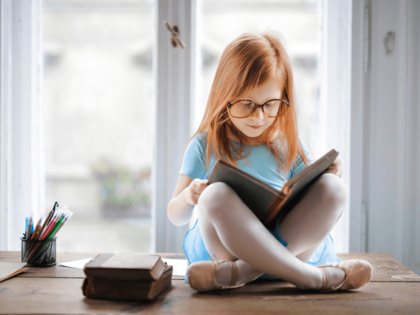 Child sitting by a window, independently reading at her own reading level.
