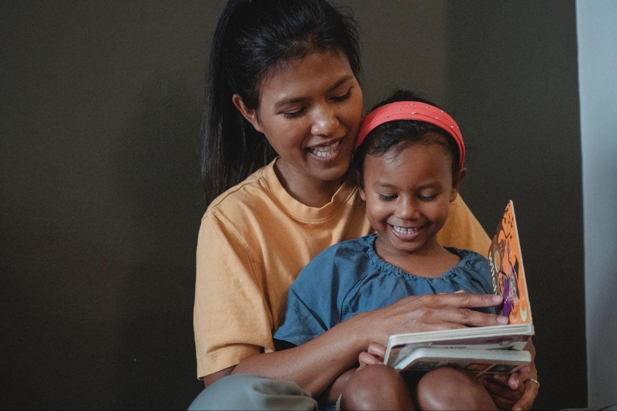Mother and daughter read a book together to boost reading comprehension.