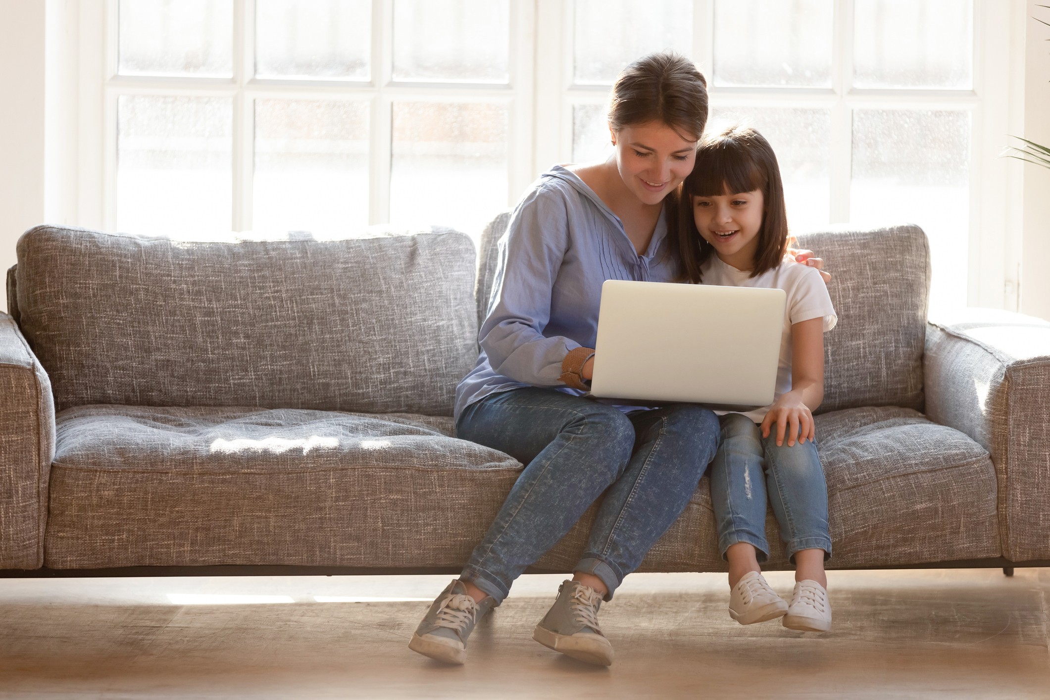 Parent and child sitting on the couch on a laptop together