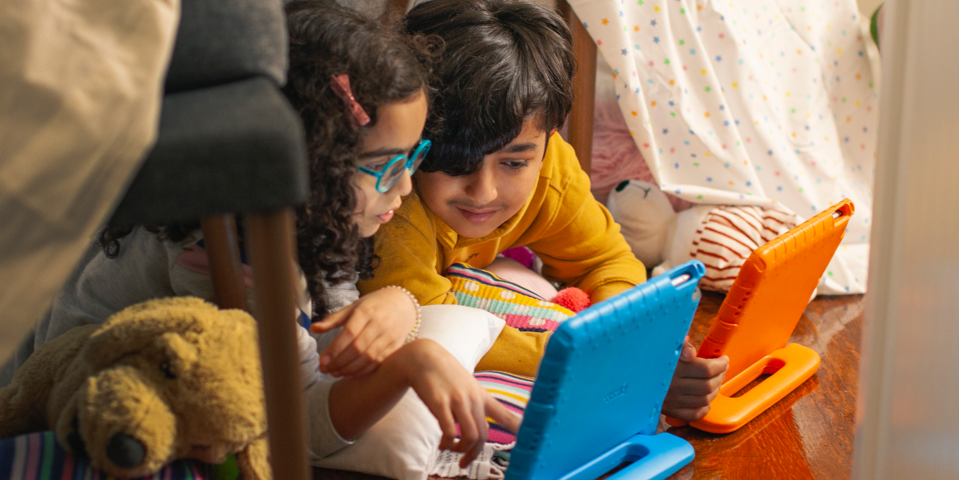 Two children playing on tablet devices.